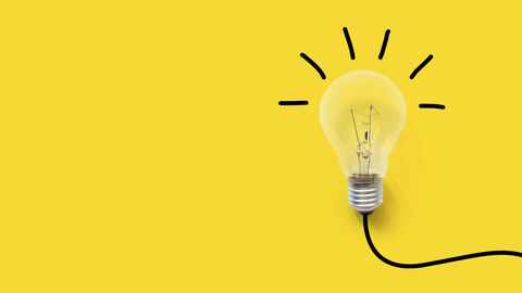 Ideen Gelber Hintergrund. Auf der rechten Seite ist eine Glühbirne mit Kabel zu sehen.