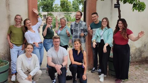 Gruppenbild des 7. Austauschtreffens der Bewegungskoordinierenden Gruppenbild des Austauschtreffens im Garten vor einem Torbogen