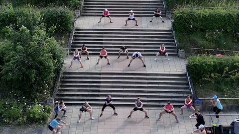 Menschen machen angeleitet Sport auf einer Treppe im öffentlichen Raum