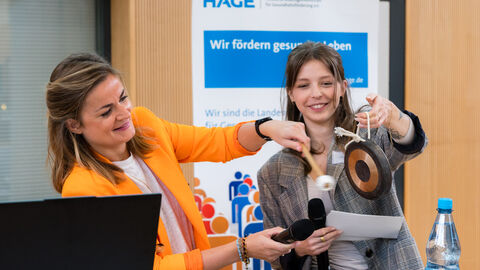 Frauen schlagen gemeinsam Gong an Rednerpult