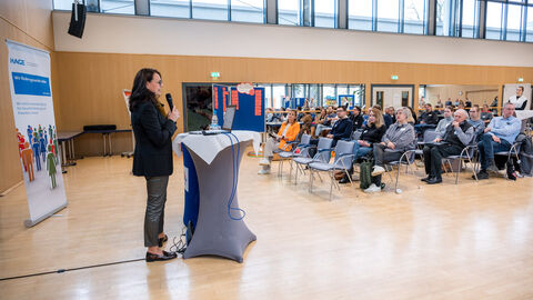 Frau an Rednerpult, Plenum hat die Aufmerksamkeit auf Sie gerichtet