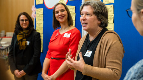 Drei Frauen vor der Pinnwand sprechen mit Gruppe