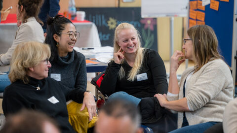 Vier Personen tauschen sich mit Sitznachbarn und -nachbarinnen aus 