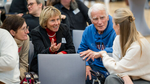Vier Personen tauschen sich mit Sitznachbarn und -nachbarinnen aus. 