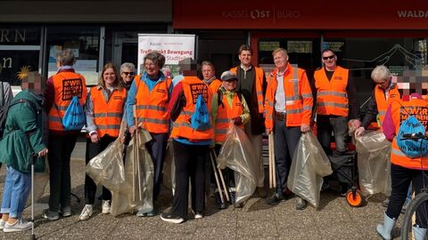 Menschen in Warnwesten mit Müllsäcken in der  Hand