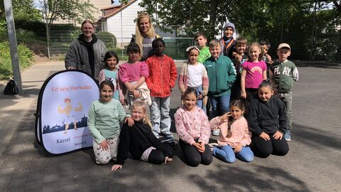 Gruppenbild von Kindern und Erwachsenen in einem Hof. 