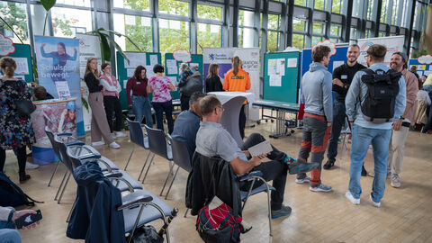 Teilnehmende tauschen sich zwischen den Ständen auf dem Markt der Möglichkeiten aus.