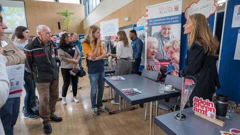 Teilnehmende tauschen sich zwischen den Ständen auf dem Markt der Möglichkeiten aus.