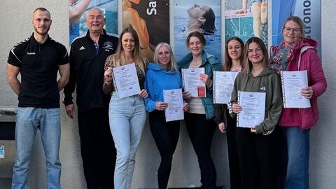 Gruppenbild mit acht Personen, die Urkunden in den Händen halten.